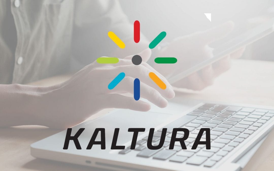 Kaltura logo. Someone holding a tablet in front of a laptop in the background.