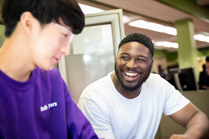 Student smiles as Tech Tutor talks with him