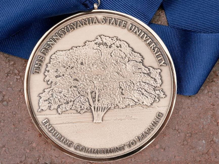 The Impact Award medal has a tree in the center and the words "Pennsylvania State University" and "Enduring Commitment to Learning"